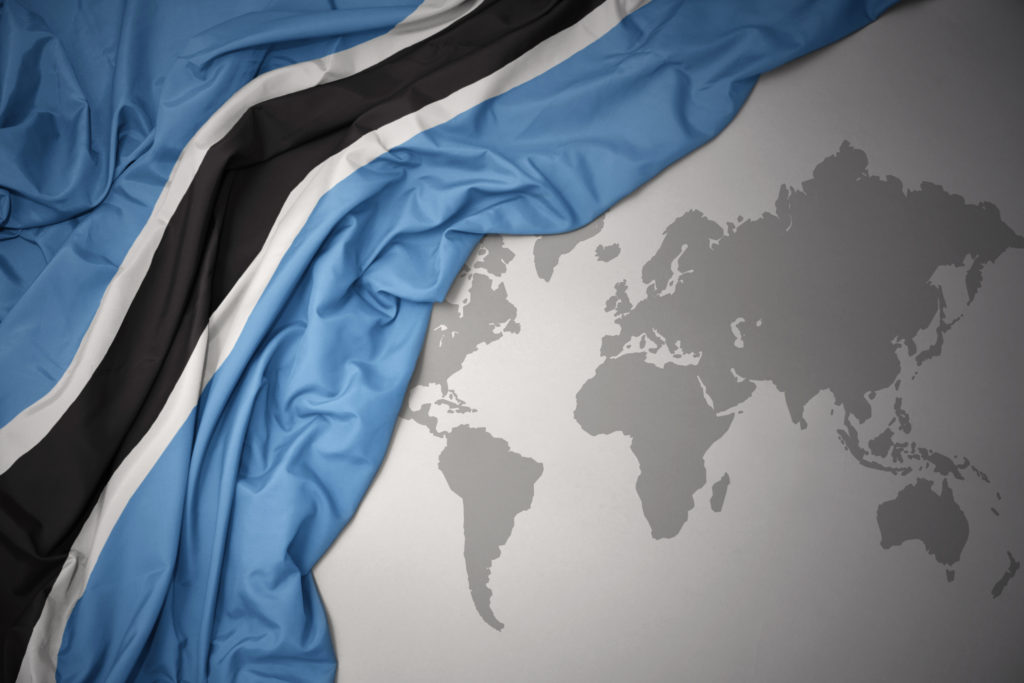 A flag of botswana is shown on top of the world map.