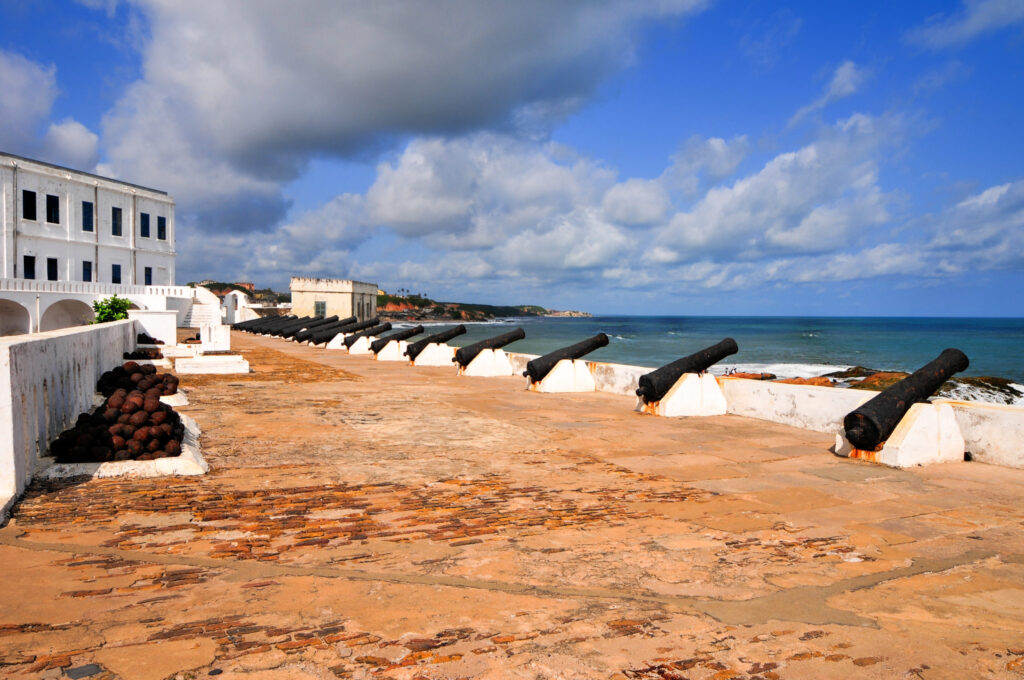 A beach with several large cannons on the sand.